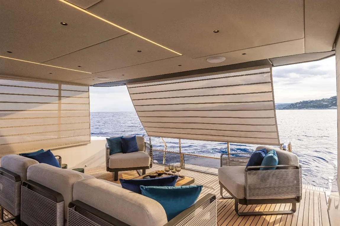 Luxe yacht deck seating area with plush cushions, panoramic ocean view, and retractable shades for comfort and style.